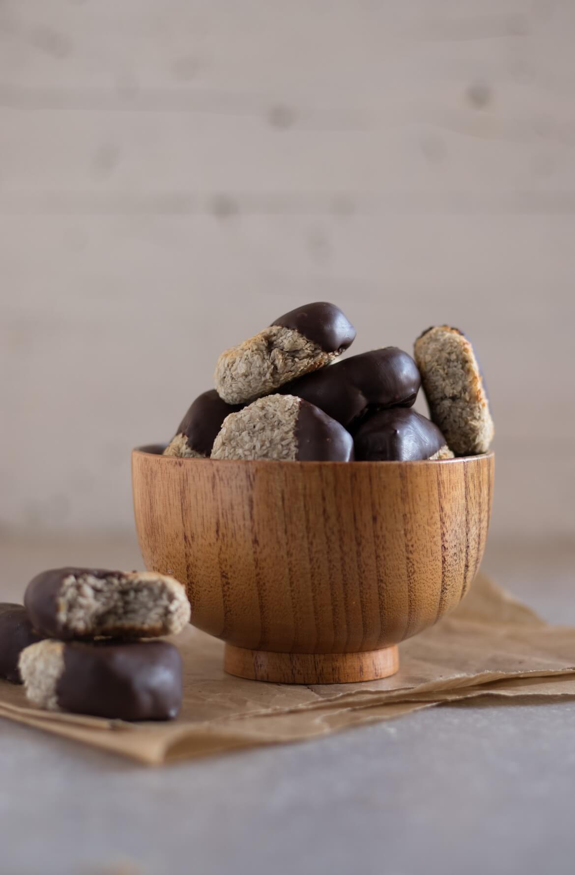 Uma taça com vários biscoitos de coco cobertos com chocolate.