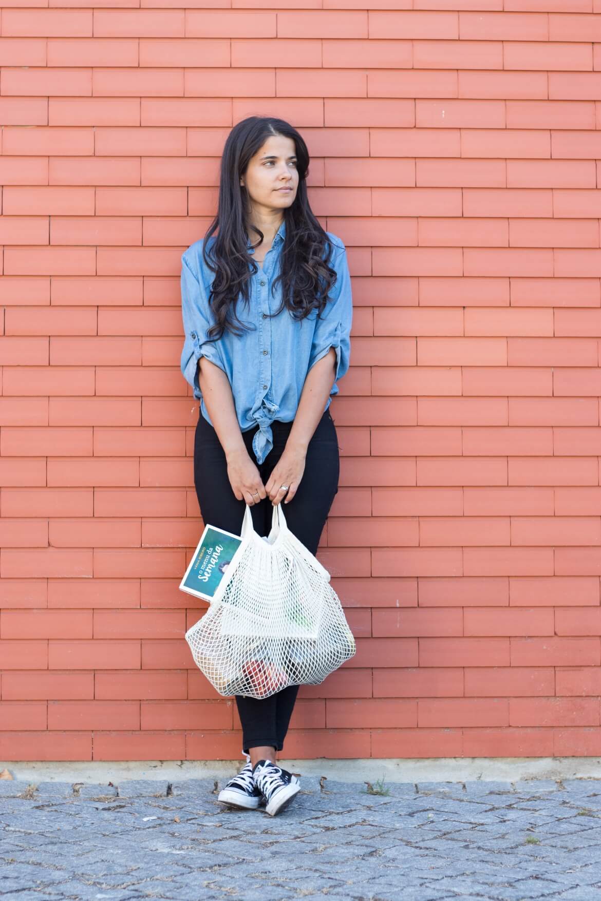 Pessoa com uma mala reutilizável e um livro sobre planeamento, representando os benefícios de planear refeições de forma consciente e sustentável