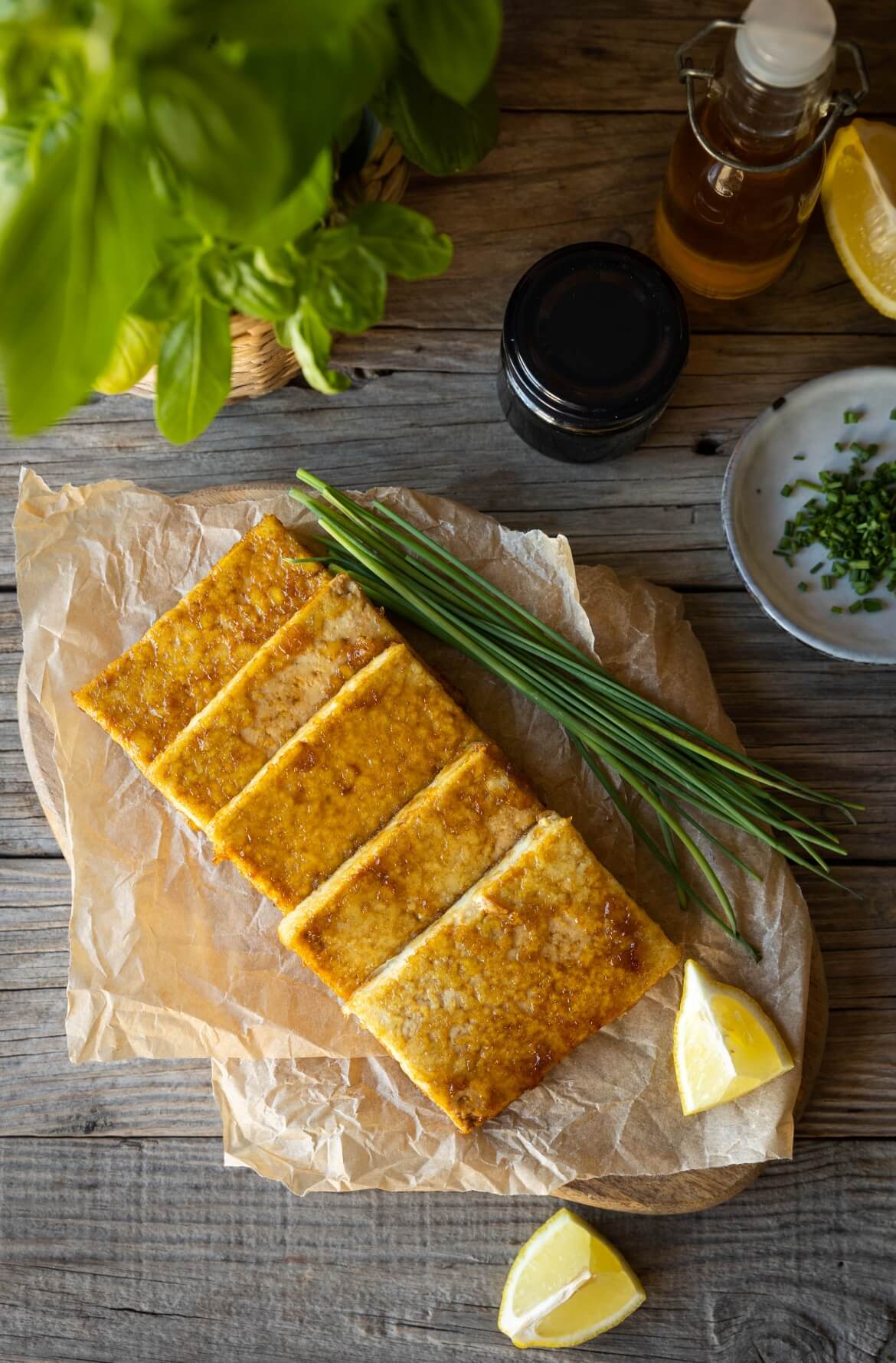 Bifes de tofu dispostos numa tábua com cebolinho e limão