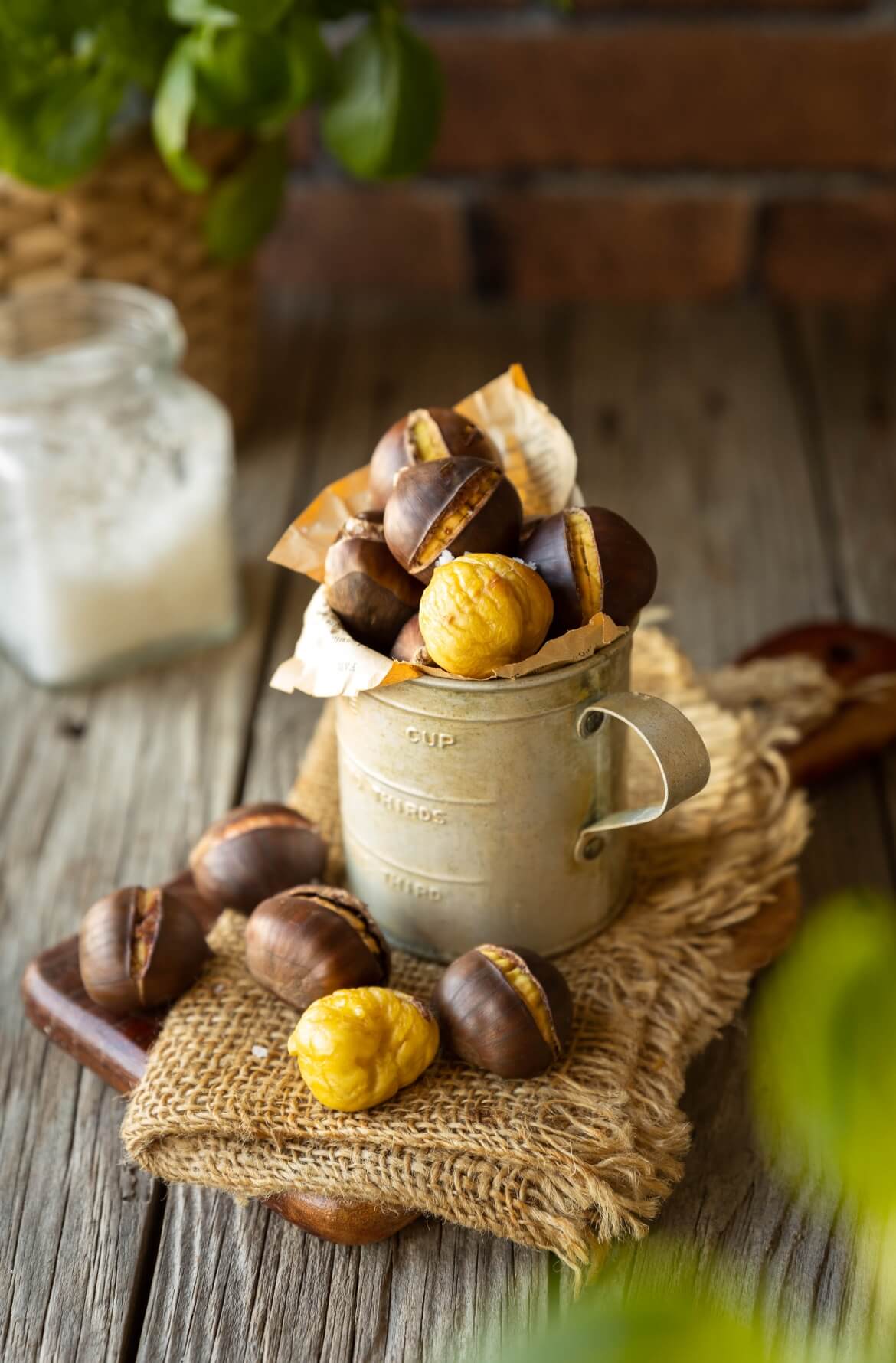 Um copo num ambiente rústico e com algumas castanhas assadas na airfryer. 